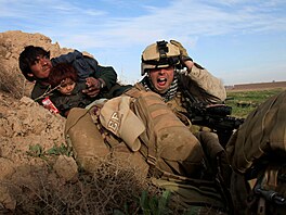 Americký voják chrání afghánského muže s dítětem před palbou Tálibánu v...