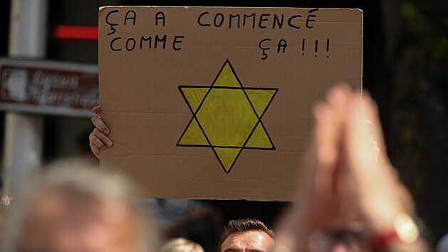 Muž na protestu proti průkazu zdraví v Reims drží transparent se žlutou Davidovou hvězdu. (31. července 2021)