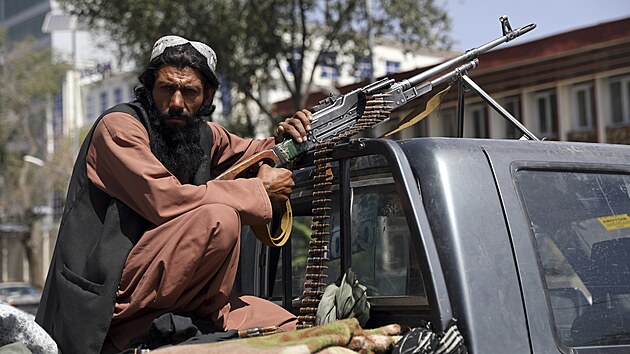 Bojovník Tálibánu sedí na zadní části vozidla s kulometem před hlavní branou vedoucí do kábulského prezidentského paláce. (16. srpna 2021)
