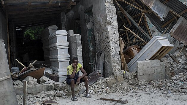 Muž sedí před zříceným pohřebním ústavem ve městě Les Cayes. (16. srpna 2021)