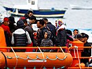 Migranti ekají na vylodní z plavidla panlské pobení stráe v pístavu na...