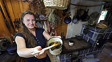 Lenka Reicheltová vaří bylinná mýdla v kuchyni na kachlových kamnech.