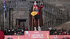 Primož Roglič oblečený jako poutník na pódiu před katedrálou v Santiago de...