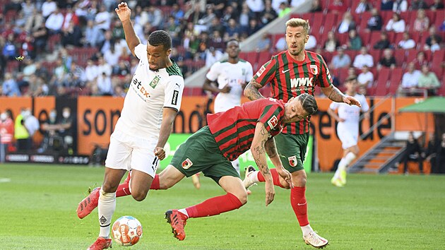 Alassane Plea z Mnchengladbachu pechz pes Jeffreyho Gouweleeuwa (uprosted) a Niklase Dorsche z Augsburgu.