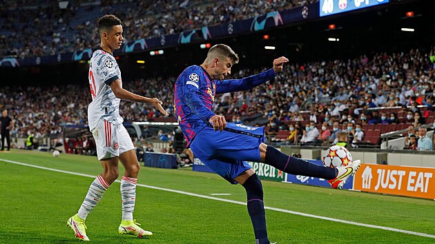 Gerard Piqu� z Barcelony odkop�v� balon p�ed Jamalem Musialou z Bayernu.