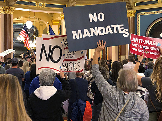 Ameriané protestující proti povinnému okování, testování a roukám v...