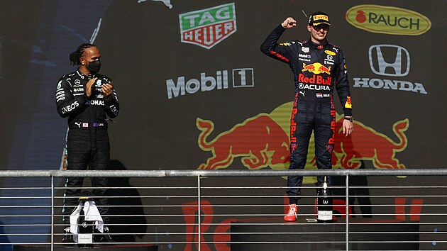 Max Verstappen (vpravo) se usmívá po vítězství na Velké ceně USA, vlevo od něj stojí a tleská druhý Lewis Hamilton.