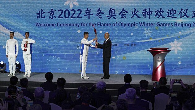 Nejvyšší představitel pekingského městského výboru Komunistické strany Číny Cchaj Čchi předává pochodeň s olympijským ohněm jednomu z dobrovolníků.