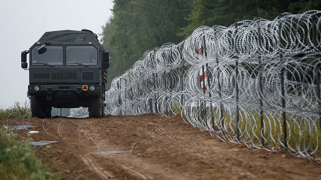 Pohled na vozidlo vedle plotu postaveného polskými vojáky na hranici mezi...