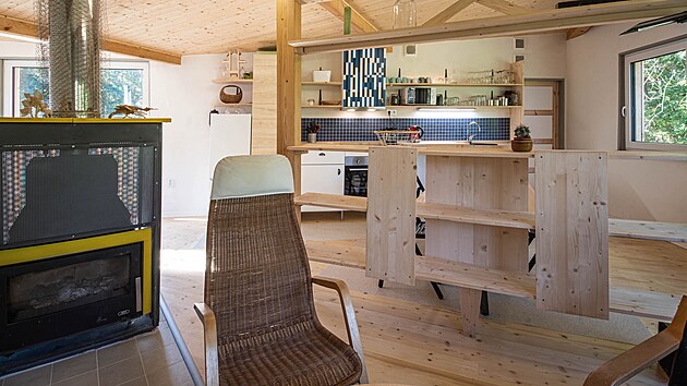 Obytná místnost spojuje obývací pokoj, kuchyni i jídelnu. Prostor je obložený smrkovým dřevem – na podlaze i v podhledu. Krbová vložka je součástí hybridního vytápění domu.