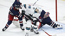 Branká Connor Hellebuyck z Winnipegu elí anci Tomáe Hertla ze San Jose....