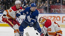 Dan Vladař v brance Calgary Flames v zápase s  Toronto Maple Leafs. Atakuje ho...