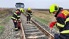 Drá�ní hasi�i likvidují následky st�etu motorového vozu s p�eká�kou na trati...