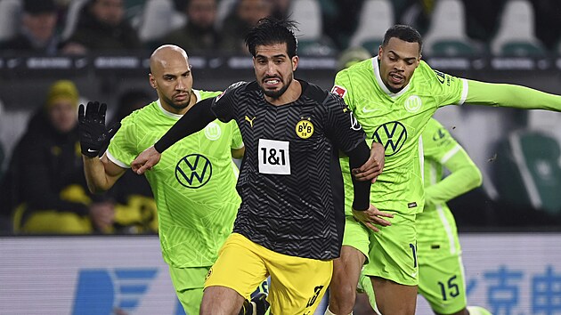 Emre Can z Dortmundu vede balon bráněný dvěma hráči Wolfsburgu.