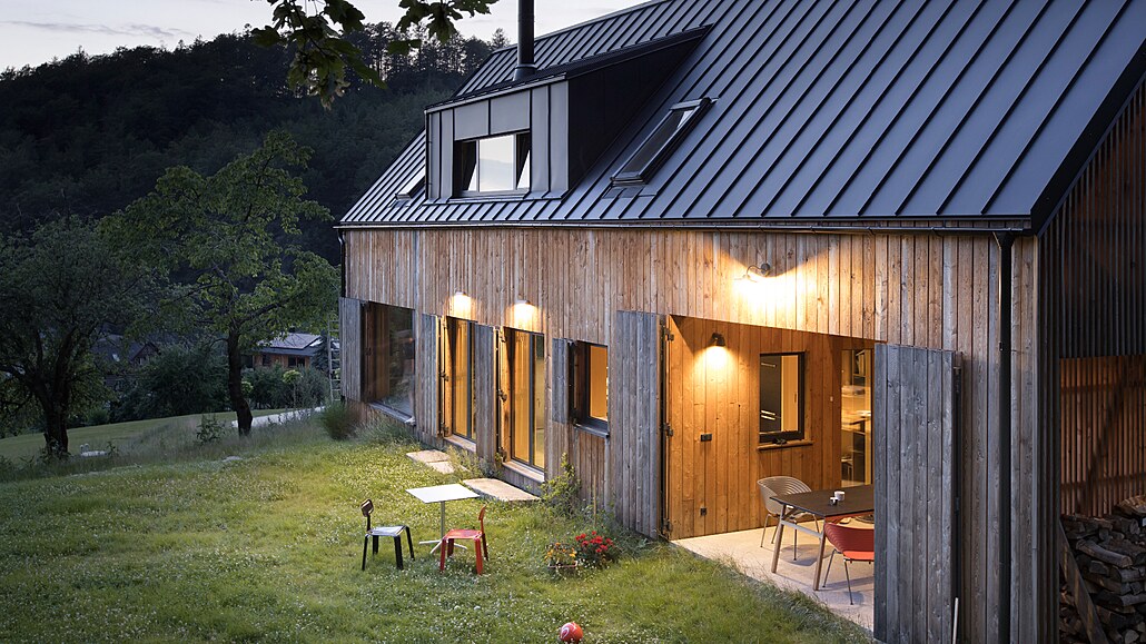 Jednoduchá modřínová fasáda, tmavá sedlová střecha a tradiční vikýř s vyhlídkou...