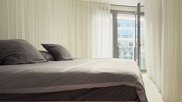 Nepravidelný půdorys ložnice rodičů je zcelen světlým obvodovým závěsem okolo manželské postele. 