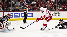 Dylan Larkin z Detroitu pálí, proti nmu branká New Jersey Akira Schmid.