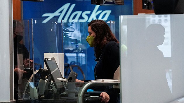 Zamstnankyn leteck spolenosti Alaska Airlines odbavuje zkaznka na check-inu mezinrodnho letit v Los Angeles. Tchto americkch aerolinek se omezen let kvli omikronu dotklo nejvce. (23. prosince 2021)