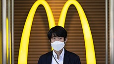 Muž v roušce před pobočkou fast foodu na tokijském hlavním nádraží. Řetězec...