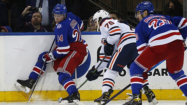 Evan Bouchard (75) z Edmonton Oilers bojuje s pesilou hr New York Rangers, vlevo Kaapo Kakko, vpravo Chris Kreider.