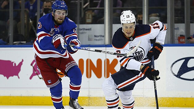 Alexis Lafreniere (vlevo) z New York Rangers se sna zastavit Jesseho Puljujrviho z Edmonton Oilers.