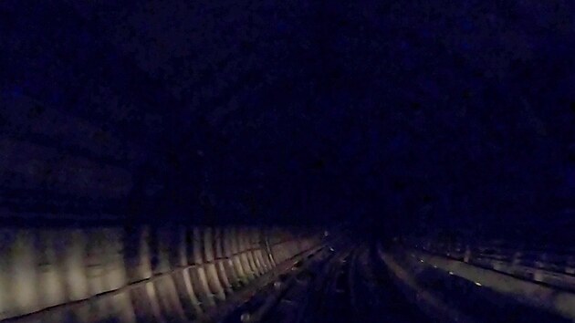 Záběr kamery v tunelu osvíceném jen reflektory vozu metra
