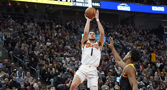 Devin Booker z Phoenixu pi stelb, brání ho  Hassan Whiteside z Utahu.