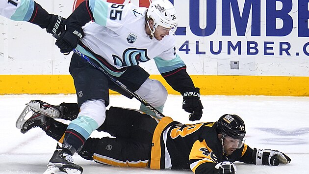 Dominik Simon (49) z Pittsburgh Penguins podražený v zápase s Seattle Kraken. K ledu ho poslal Jeremy Lauzon (55).