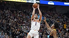 Devin Booker z Phoenixu pi stelb, brání ho  Hassan Whiteside z Utahu.