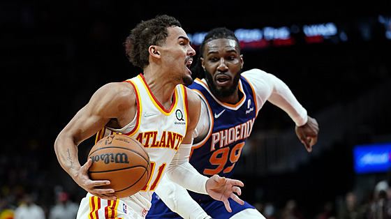 Rozbhnutý Trae Young z Atlanty míí pod ko, stíhá ho Jae Crowder z Phoenixu.