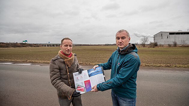 Organizátoři petice za vyhlášení referenda Nathaniel Filip de Aras a David Chládek stojí před pozemky, na kterých by se mělo stavět.