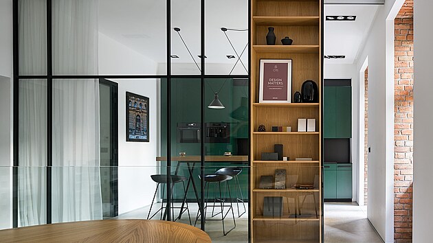 Prosklená stěna a knihovna s posuvnými dveřmi pak rozděluje kuchyň a jednací místnost.