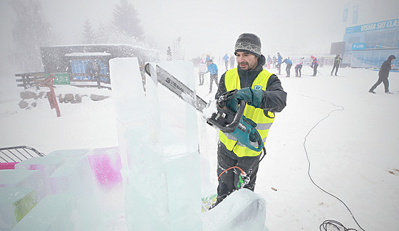 Umělecký sochař vytváří z ledových bloků bar, křeslo a stěnu s motivem hor.