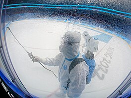 Pracovník dezinfikuje ledovou plochu po enském hokejovém zápase o zlatou...