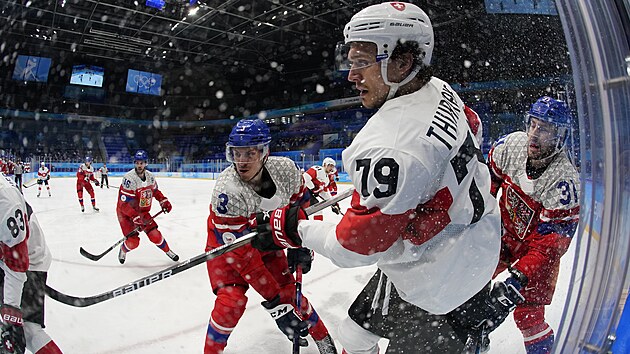 Olympijský turnaj mužů v ledním hokeji. Švýcar Calvin Thurkauf (79) bojuje v rohu s Čechy Ronaldem Knotem (3) a Lukášem Klokem (31). (11. února 2022)