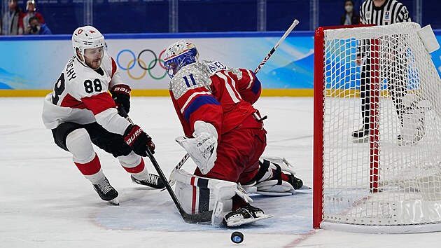 Olympijský turnaj mužů v ledním hokeji. Brankář České republiky Šimon Hrubec (11) blokuje střelu Švýcara Christopha Bertschyho (88) při samostatných nájezdech. (11. února 2022)