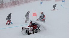 Pořadatelé odklízejí sníh před začátkem prvního kola obřího slalomu v Pekingu.