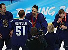 Finský hokejový obránce Ville Pokka (2) líbá zlatou olympijskou medaili. Vedle...
