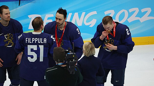 Finsk hokejov obrnce Ville Pokka (2) lb zlatou olympijskou medaili. Vedle nj mezitm spoluhri z obrany Niklasi Frimanovi (3) gratuluje kapitn Valtteri Filppula (51). Vlevo ek dal bek Mikko Lehtonen.