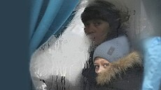 ena s díttem se dívají z okna autobusu ped odjezdem z msta Severodonck v...