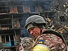 Ukrajinský voják s toulavou kokou ped zpustoenou budovou ve mst Vasilkiv...