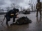 Ukrajintí vojáci zachraují vybavení z tla mrtvého ruského vojáka, který...