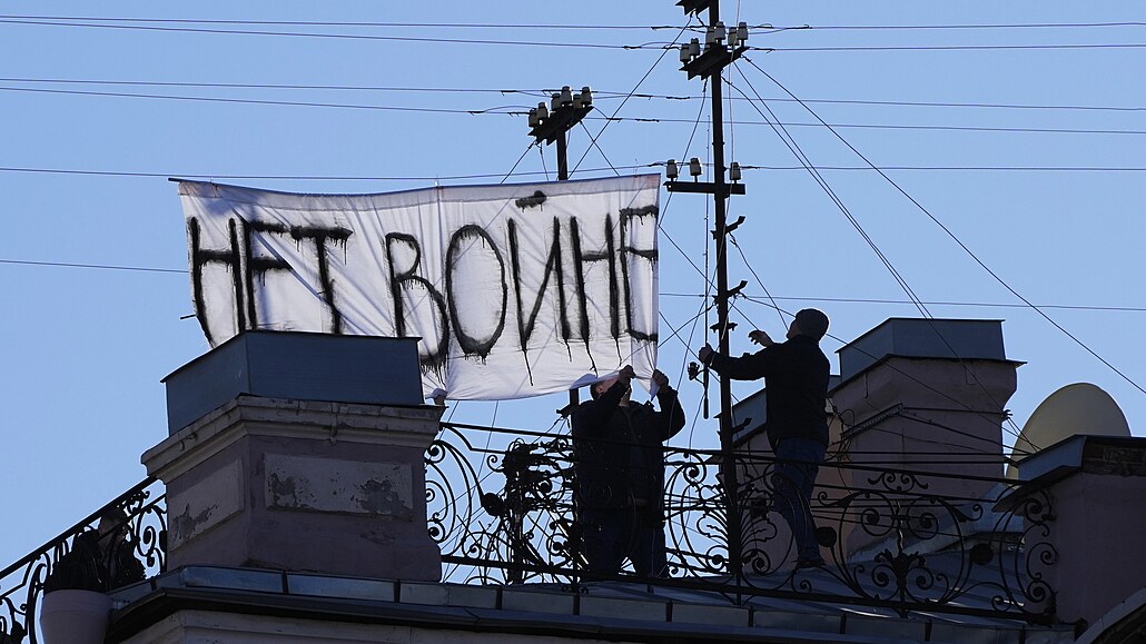 Dva mui sundávají transparent s nápisem Ne válce, který nkdo vyvsil na stee budovy na Nvském prospektu v Petrohrad 1. bezna 2022, týden po zaátku konfliktu na Ukrajin.