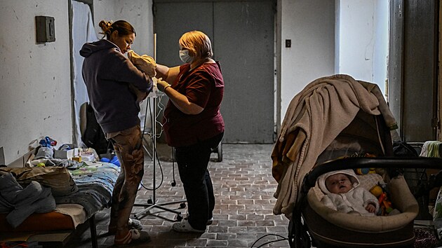 Zdravotn sestra peuje o dt v suternu nemocnice v Kyjev, kam museli zdravotnci dti pesunout kvli ruskmu ostelovn. (28. nora 2022)