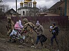 Ukrajintí vojáci pomáhají prchající rodin pekroit eku na pedmstí Kyjeva....