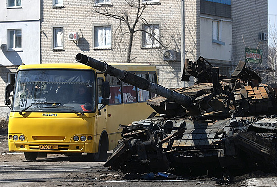 Autobus jede vedle zničeného tanku. Ukrajina se brání ruské invazi. (21. března...