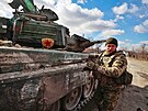 Ukrajinský voják stojí vedle ukoistného ruského tanku T-72 na pedmstí...