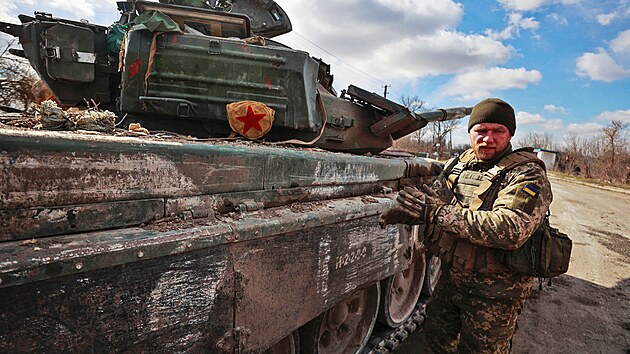 Ukrajinský voják stojí vedle ukořistěného ruského tanku T-72 na předměstí...