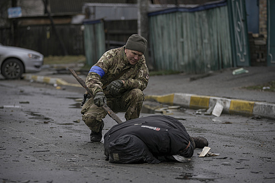 Ukrajinský voják u tla mrtvého civilisty po osvobození msta Bua v Kyjevské...