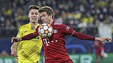 Thomas Müller z Bayernu si posouvá mí hrudníkem ped Juanem Foythem z...